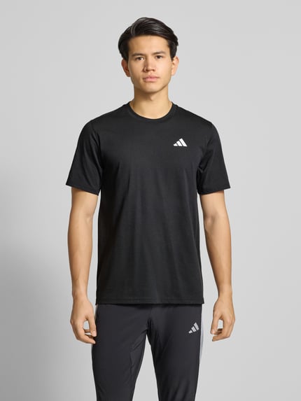 Männermodel trägt T-Shirt mit Logo und Rundhalsausschnitt von adidas Training in Schwarz, Regular-Fit, Material-Mix, Ganzkörperansicht von vorne. Rückenlänge bei Größe M: 73 cm.