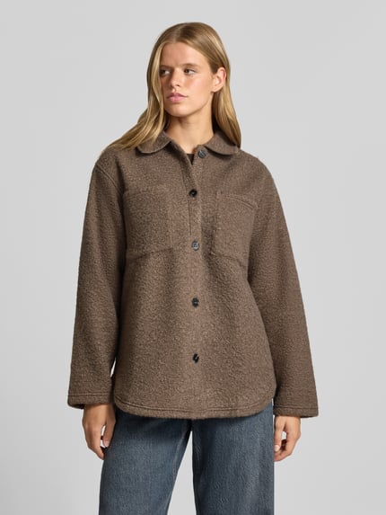 Frauenmodel trägt braune Relaxed Fit Fleecejacke mit aufgesetzten Taschen von PIECES, weiche Textur, Ganzkörperansicht von vorne.