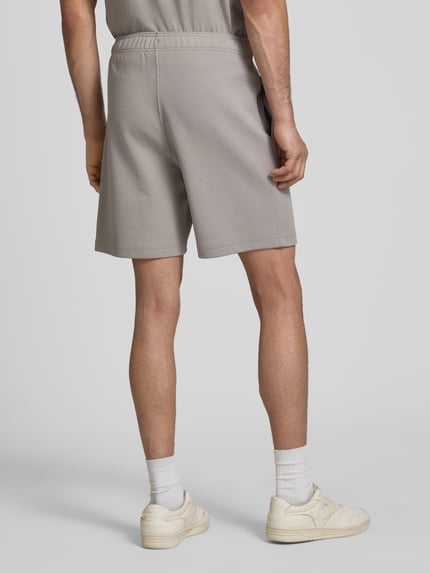 Männermodel trägt Shorts mit elastischem Bund und Label-Stitching von CHAMPION im Regular Fit aus Baumwoll-Mix, Ganzkörperansicht Rückansicht.