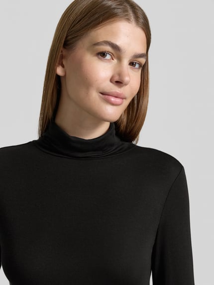 Kobiece model prezentuje Slim Fit Longsleeve aus elastischem Baumwoll-Mix Modell 'OKTOBER' od COMMA, czarny, miękka tekstura, krój slim fit, elastyczny bawełniany materiał, z golfem, długość pleców w rozmiarze 36: 58 cm, zbliżenie na górną część ciała z przodu.