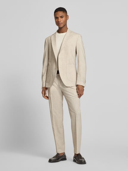 Männermodel trägt Slim Fit 2-Knopf-Sakko mit Viskose-Anteil Modell 'DATI' van CINQUE in beige met reverskraag en opgestikte zakken, volledig lichaam van voren. Context: elastische materiaalmix met viscose, 2-knopssluiting, borstzak, ruglengte 72 cm, schouderbreedte 44 cm, mouwlengte 65 cm.