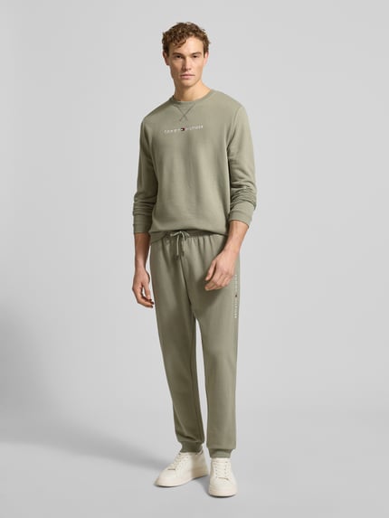 Männermodel trägt Regular Fit Sweathose aus Baumwoll-Mix von Tommy Hilfiger, Optik: Unifarben, seitliche Eingrifftaschen, Ganzkörperansicht von vorne.
