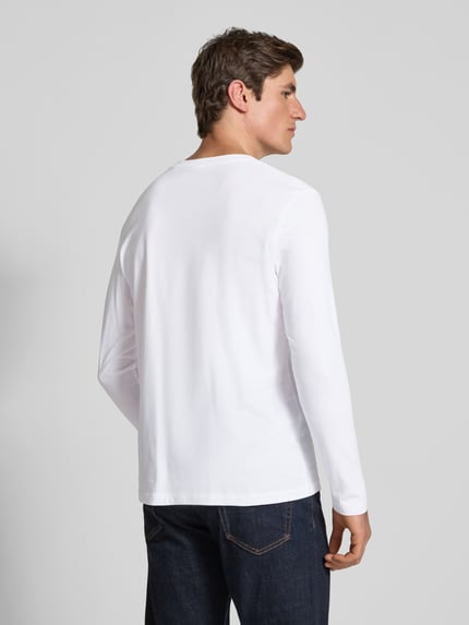 Männermodel trägt weißes Langarmshirt mit dezentem Logo-Detail von S.OLIVER CASUAL, unifarben, Rundhals, Ganzkörperansicht Rückansicht.