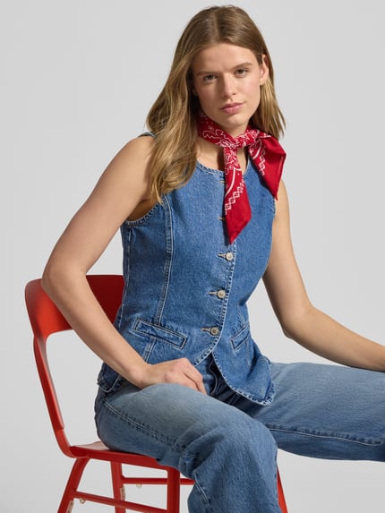 Frauenmodel trägt Jeansweste aus reiner Baumwolle Modell 'GUILINA' von ONLY in Denim-Optik mit Rundhals, Knopfleiste und Paspeltaschen, Nahaufnahme Oberkörper.