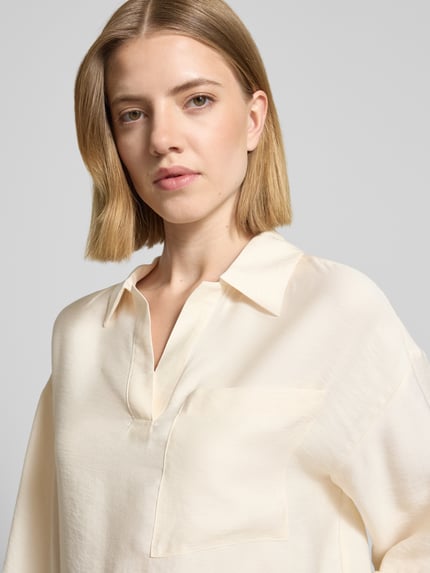Frauenmodel trägt Bluse mit Brusttasche und V-Ausschnitt Modell 'Felmara' von OPUS im Modal-Mix in Creme, Nahaufnahme Oberkörper.