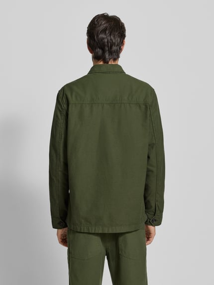 Männermodel draagt Regular Fit Hemdjacke aus reiner Baumwolle van Tommy Hilfiger in effen groen, lange mouwen, borstzakken, noppenstructuur, Ganzkörperansicht Rückansicht.
