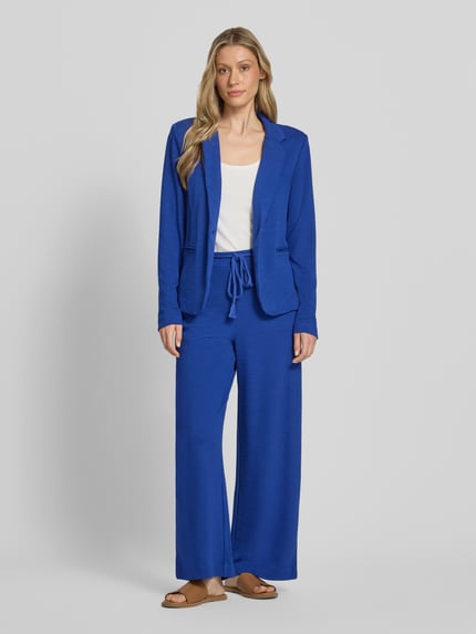 Frauenmodel trägt Wide Fit Stoffhose aus Viskose-Mix Modell 'Lumina' von ICHI mit Strukturmuster und Abnehmbare Stoffkordel, Ganzkörperansicht von vorne. Bundweite 39 cm, Innenbeinlänge 72 cm bei Größe S, Gesäßtaschen.
