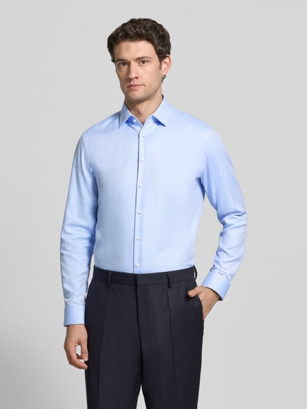 Männermodel trägt Slim Fit Businesshemd aus reiner Baumwolle von Jake*s in Hellblau, unifarben, Kentkragen, Ganzkörperansicht von vorne.