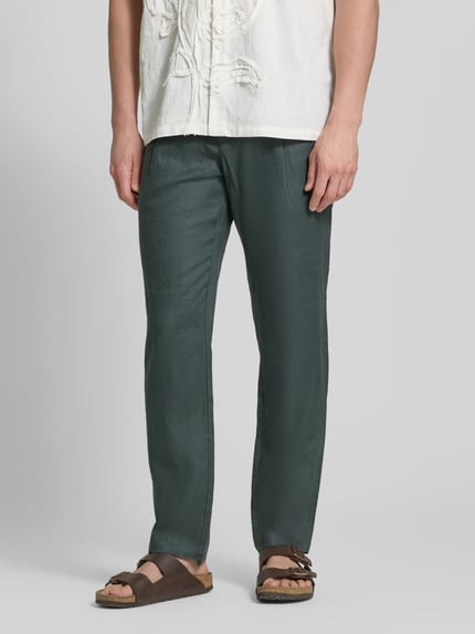 Männermodel trägt Tapered Leinenhose mit Gürtelschlaufen Modell 'OSBY JOGGER' von Marc O'Polo in Optik: Unifarben, Passform: Tapered, mit Bundfalte, Knopf und verdecktem Reißverschluss, seitlichen Eingrifftaschen und Gesäßtaschen aus Material: Leinen. Ganzkörperansicht von vorne.
