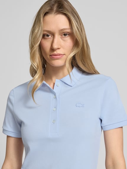 Frauenmodel trägt Slim Fit Polokleid aus Baumwoll-Mix von Lacoste in Hellblau, unifarben, Piqué-Textur, Nahaufnahme Oberkörper.