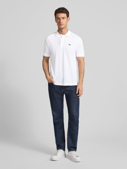Męski model nosi białe Poloshirt mit Label-Stitching Modell 'L.12.12 CORE' od LACOSTE, regular fit, gładka bawełna, całkowity widok z przodu.