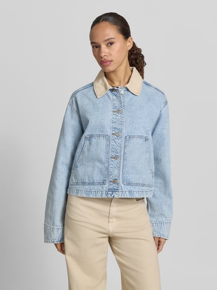 Vrouwenmodel draagt Cropped Jeansjacke mit Umlegekragen van GAP in lichtblauw, puur katoen, knoopsluiting, steekzakken, vooraanzicht bovenlichaam. Ruglengte maat S 50 cm, schouderbreedte 50 cm, borstwijdte 55 cm, mouwlengte 60 cm.