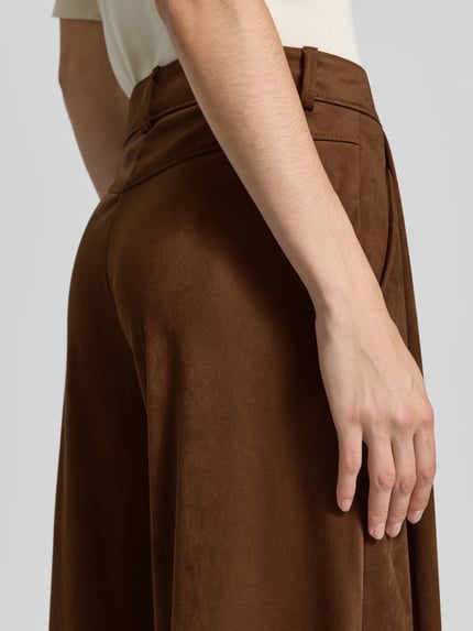 Frauenmodel trägt Wide Leg Kunstlederhose in Velours-Optik Modell 'C_Takora2' von BOSS Orange, braun, samtige Textur, Nahaufnahme Oberkörper.