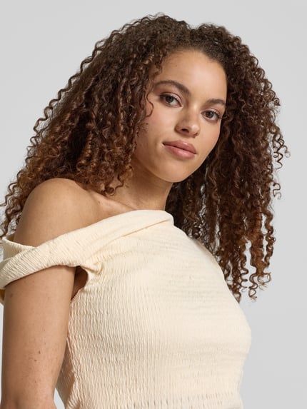 Frauenmodel trägt T-Shirt mit asymmetrischem Ausschnitt von Jake*s Collection, Material-Mix mit Stretch-Anteil, Smok-Detail, Nahaufnahme Oberkörper.