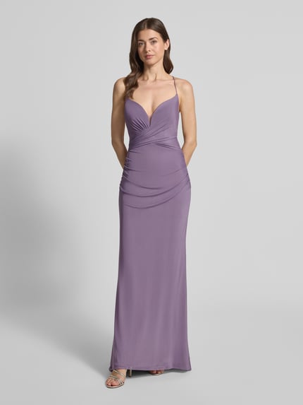 Frauenmodel trägt Abendkleid mit Rückenausschnitt von Laona in Lila mit Spaghetti-Trägern, V-Ausschnitt, Raffung, blickdichtem Unterrock, taillierter Passform, Schnürverschluss und Nahtreißverschluss, Ganzkörperansicht von vorne.