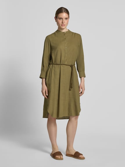Frauenmodel trägt Midikleid aus Leinen-Mix mit Bindegürtel von Fynch-Hatton, olivgrün, Knopfleiste, Mao-Kragen, Ganzkörperansicht von vorne. Taillierter Schnitt, Leinen-Viskose-Anteil, abgerundeter Saum, Rückenlänge 112 cm, Brustweite 52 cm, Ärmellänge 52 cm.