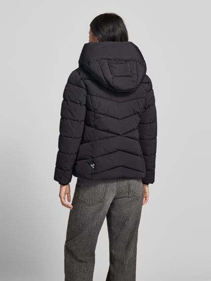 Frauenmodel trägt schwarze Steppjacke mit Kapuze und Label-Detail Modell 'HERSCH2' von khujo, gesteppt, Rückenansicht, Ganzkörperansicht Rückansicht.