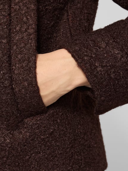Frauenmodel trägt Kurzmantel mit Stehkragen Modell 'SC-GISA 1' von SOYACONCEPT in einfarbigem Dunkelbraun mit strukturierter Bouclé-Oberfläche, Detailaufnahme Nahaufnahme Oberkörper, KI-modifiziertes Bild.