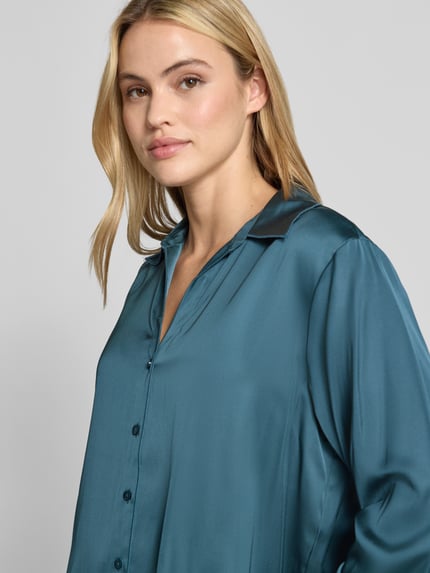 Vrouwenmodel draagt Regular Fit Bluse aus Viskose-Mix mit V-Ausschnitt van COMMA, blauw glanzende stof, knoopsluiting, overhemdkraag, Nahaufnahme bovenlichaam.