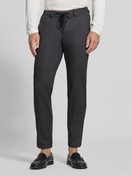 Männermodel trägt dunkelgraue Tapered Fit Jogpants aus reiner Baumwolle Modell 'Phil' von Brax, Herren Weite Hose, Ganzkörperansicht von vorne.