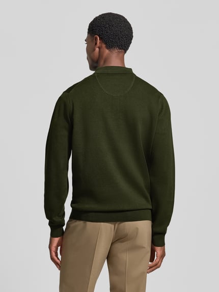 Männermodel trägt Strickpullover mit Polokragen und Knopfleiste von Fynch-Hatton in Dunkelgrün zu beigefarbener Hose, reine Baumwolle, Rückenlänge und Ärmellänge bei Größe M, Regular Fit, Label-Stitching, Ganzkörperansicht Rückansicht.