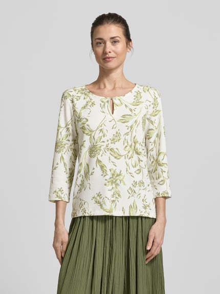 Vrouwenmodel draagt Regular Fit T-shirt met all-over motief van s.Oliver RED LABEL, ronde hals met druppelvormige hals, 3/4-mouwen, crinkle materiaalverwerking, kleur wit met groen patroon, textuur zichtbaar. Ganzebody aanzicht van voren.