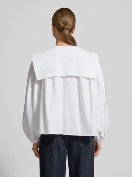 Kobieta modelka nosi białą Hemdbluse mit Matrosenkragen od Polo Ralph Lauren z bawełny, luźny krój, bufiaste rękawy, widok całej sylwetki od tyłu.