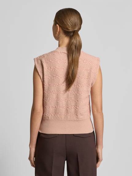 Frauenmodel trägt Strickweste mit Rundhalsausschnitt von Scotch & Soda aus Baumwoll-Mix, Slim-Fit, Rückenlänge 51 cm, Ganzkörperansicht Rückansicht.