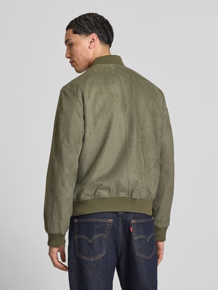 Männermodel trägt Bomberjacke in Leder-Optik mit Stehkragen von Jack & Jones in Khaki, Regular-Fit, Eingrifftaschen, Rückenansicht. Kontext: Herren Bomberjacke mit Reißverschluss, Rückenlänge 64 cm, Schulterbreite 45 cm, Brustweite 52 cm, Ärmellänge 67 cm.
