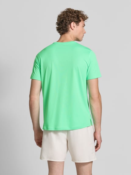 Männermodel trägt T-Shirt mit Logo-Print Modell 'CORE' von ASICS TIGER in Hellgrün, glatte Oberfläche, Ganzkörperansicht Rückansicht. Herren T-Shirt, gerader Schnitt, Rundhalsausschnitt, Rückenlänge bei Größe M 72 cm.