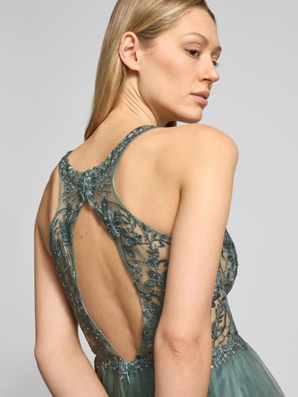 Vrouwenmodel draagt Regular Fit Abendkleid in semitransparentem Design van Laona met florale kanten details, sierstenen, halternek, mesh en open rug, detailopname rug.
