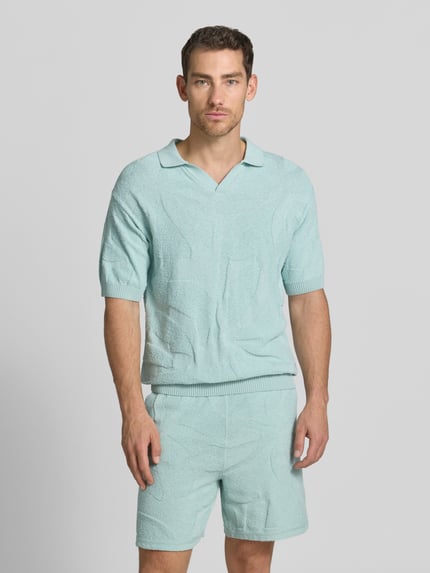 Männermodel trägt Relaxed Fit Poloshirt aus reiner Baumwolle Modell 'ASURFO' von BOSS Orange, Optik: Unifarben, Struktur, Ganzkörperansicht von vorne.
