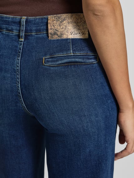 Frauenmodel trägt Flared Jeans im Used-Look mit Eingrifftaschen von Liu Jo White, dunkler Baumwoll-Elasthan-Mix, Nahaufnahme Rückansicht.