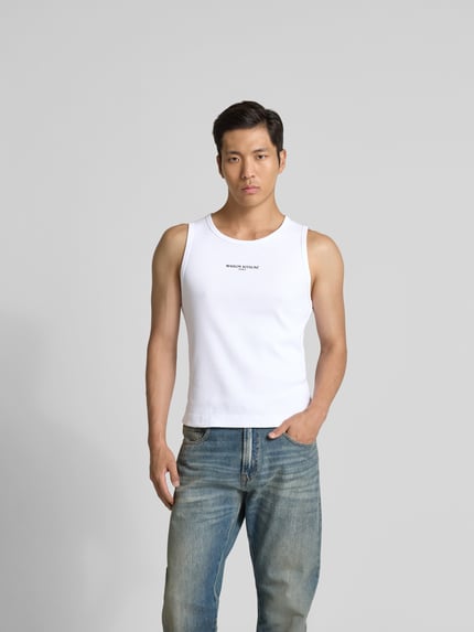Męski model nosi Top aus reiner Baumwolle von MAISON KITSUNÉ, biały, efekt prążkowania, detal z logo, krój bez rękawów, krój slim fit, długość tyłu w rozmiarze M: 61 cm, widok całej sylwetki z przodu.