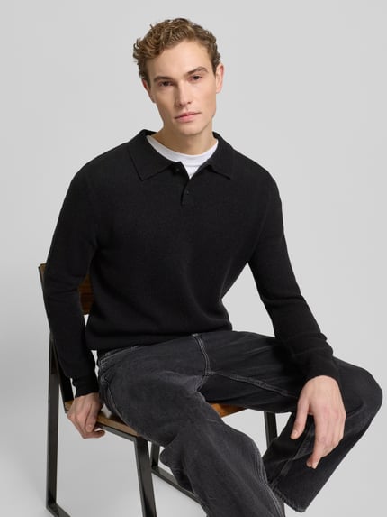Männermodel trägt Poloshirt mit gerippten Abschlüssen von Forét in Schwarz, Woll-Mix, Regular Fit, Nahaufnahme Oberkörper.