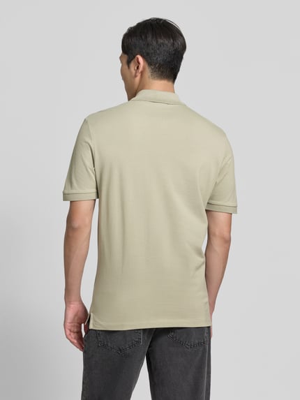 Männermodel trägt Regular Fit Poloshirt aus reiner Baumwolle Modell 'DONOS222' von HUGO, jasnobeżowy, gładka faktura, kołnierzyk polo, krótki rękaw, aplikacja z metką, bawełna, zapięcie na krótką listwę guzikową, zakończenie z rozcięciami bocznymi, wykończenie materiału: tkanina, ganzkörperansicht rückansicht