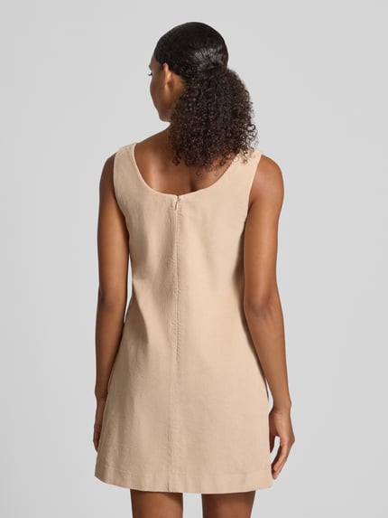 Frauenmodel trägt Slim Fit Freizeitkleid aus reiner Baumwolle von Lacoste in Beige, strukturierte Oberfläche, Ganzkörperansicht Rückansicht. Damen Freizeitkleid von Lacoste.
