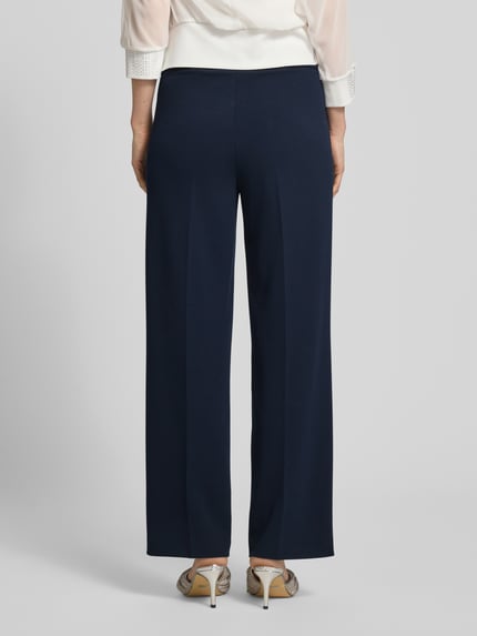 Frauenmodel trägt Stoffhose mit Bügelfalte und elastischem Bund von Vera Mont im Loose-Fit, Material-Mix mit Stretch-Anteil, Ganzkörperansicht Rückansicht.