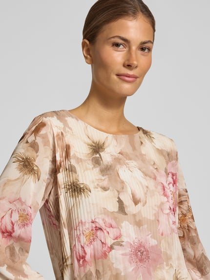 Kobieta prezentuje bluzkę Regular Fit z plisami Model 'An44nii' od ZABAIONE, wzór na całej powierzchni, okrągły dekolt, Długość tyłu 60 cm, Długość rękawów 58 cm, zbliżenie na górną część ciała.