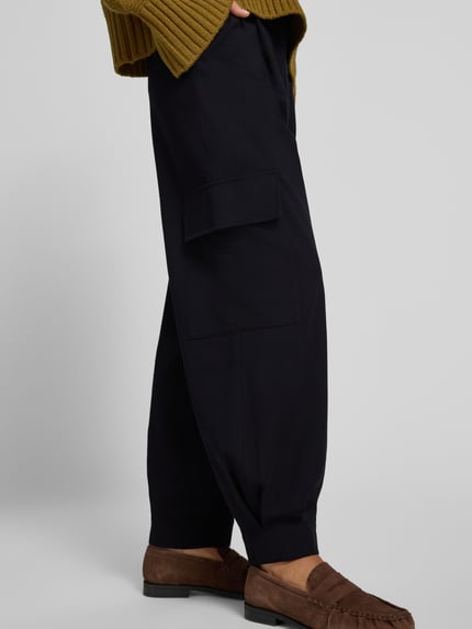 Frauenmodel trägt schwarze Cargo-Hose mit weitem Bein – curated by Vera van Erp von Style Icon Collection aus Material-Mix mit Viskose-Anteil, Loose Fit, französische Eingrifftaschen, Pattentaschen und Gesäßleistentaschen, seitliche Detailaufnahme.