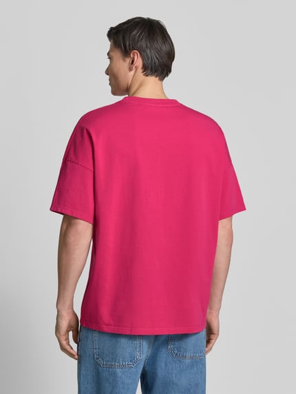 Männermodel trägt Herren T-Shirt mit geripptem Rundhalsausschnitt Modell 'FIZVALLEY' von American Vintage in Pink, Reine Baumwolle, Loose-Fit, Rückenlänge bei Größe M/L: 72 cm, Ganzkörperansicht Rückansicht.