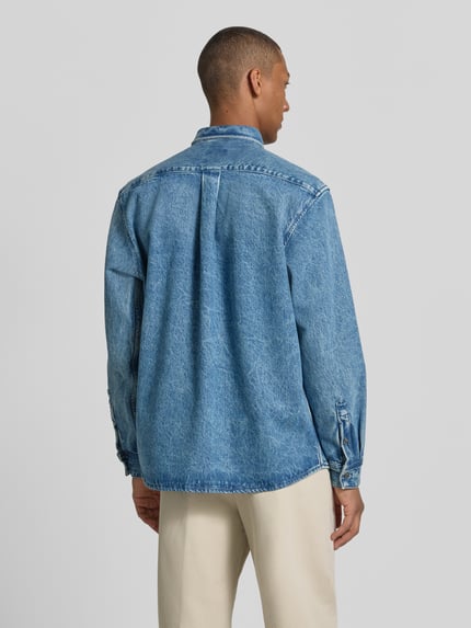 Männermodel draagt Regular Fit Jeansjacke aus reiner Baumwolle Modell 'LAMBEY BO FLEAK' van BOSS Orange in denimlook, lange mouw, platte kraag, knoopsluiting, achterpas met cacharel-plooi, borstzak, puur katoen materiaal, Ganzkörperansicht Rückansicht.