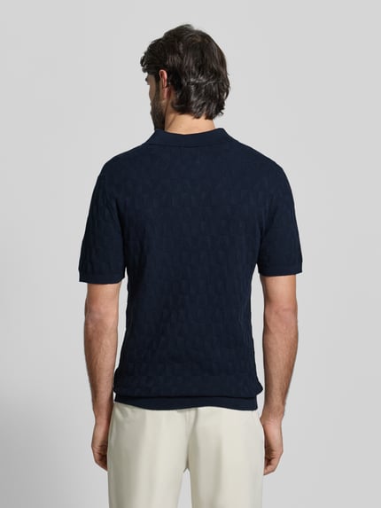 Męski model nosi Regular Fit Poloshirt mit Strukturmuster von MCNEAL z bawełny, kołnierzyk polo, imitacja dzianiny, długość tyłu 63 cm, długość rękawów 28 cm, fakturowany wzór, ciemnoniebieski, gładkie tło, całkowity widok z tyłu.