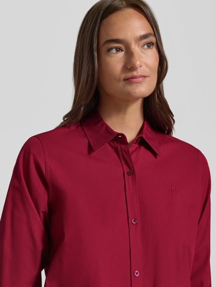 Kobieta nosi bluzkę koszulową Regular Fit Hemdbluse aus reiner Baumwolle Modell 'Essential' od HUGO, czerwona, gładka faktura, Nahaufnahme Oberkörper, bluzka damska HUGO
