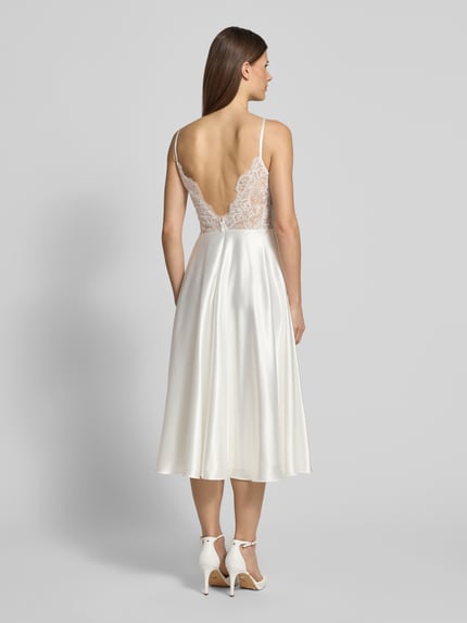 Vrouwenmodel draagt Regular Fit Kleid aus Satin mit Spitzenbesatz van Luxuar, crèmekleurig satijn, transparant kanten rug, tailleert, ruglengte 115 cm, borstwijdte 33 cm, rugrits, spaghettibandjes, geheelzicht achteraan.