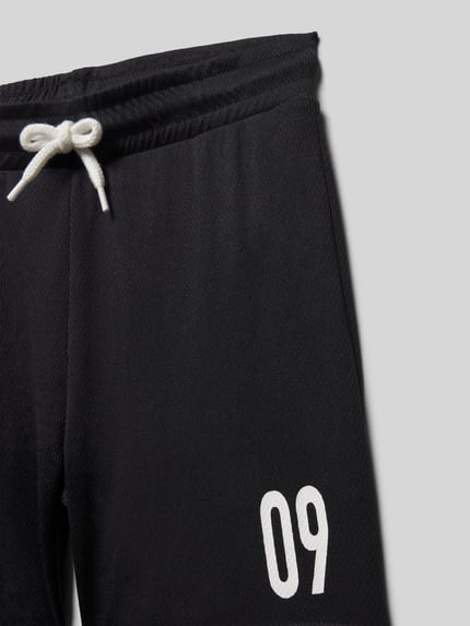 Productfoto, Regular Fit Shorts mit elastischem Bund van Blue Seven, zwart met witte print, elastische tailleband en tunnelkoord, katoenen textuur, kindermodel, korte binnenbeenlengte, maat 116, context: kinder shorts, motiefprint, bundwijdte 30 cm, binnenbeenlengte 13 cm.