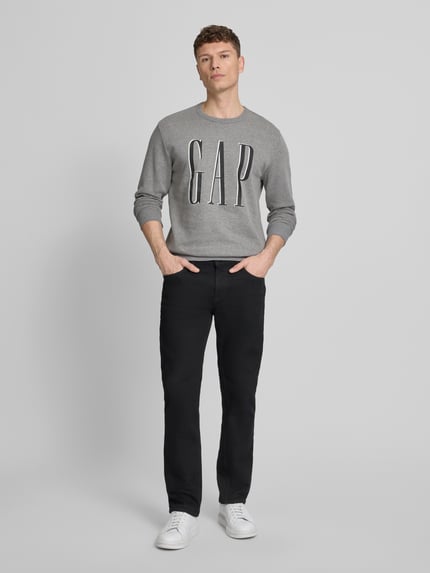 Männermodel trägt Sweatshirt mit Logo von GAP aus Baumwoll-Mix, Regular-Fit, Grau mit Rundhalsausschnitt, Ganzkörperansicht von vorne.