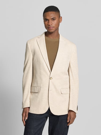 Männermodel trägt Herren Slim Fit 2-Knopf-Sakko mit Pattentaschen von MCNEAL, cremefarbener Baumwoll-Mix, Strukturmuster, Ganzkörperansicht von vorne.