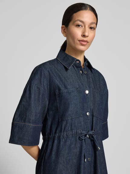 Frauenmodel trägt Knielanges Jeanskleid mit Brusttaschen von Comma in Dunkelblau, Reine Baumwolle, Hemdblusenkragen, Bindegürtel, Knopfleiste, Gerader-Schnitt, Nahaufnahme Oberkörper.