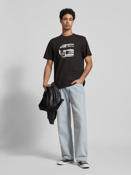 Männermodel trägt Regular Fit T-Shirt mit Logo-Print Modell 'icon' von G-Star Raw aus reiner Baumwolle, schwarze Farbe, Ganzkörperansicht von vorne.